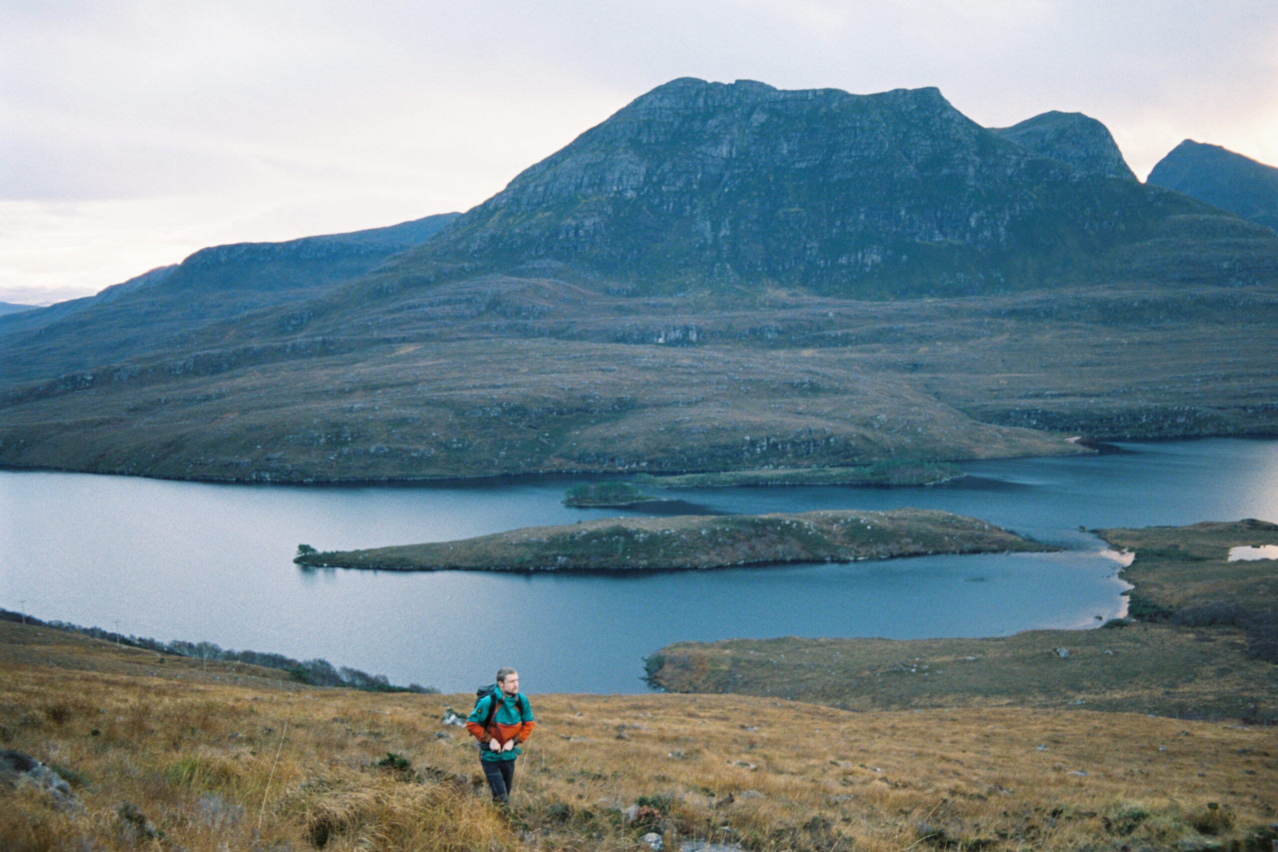 A person on the path to Stac Pollaidh, looking out over Loch Lurgainn and Sgòrr Tuath