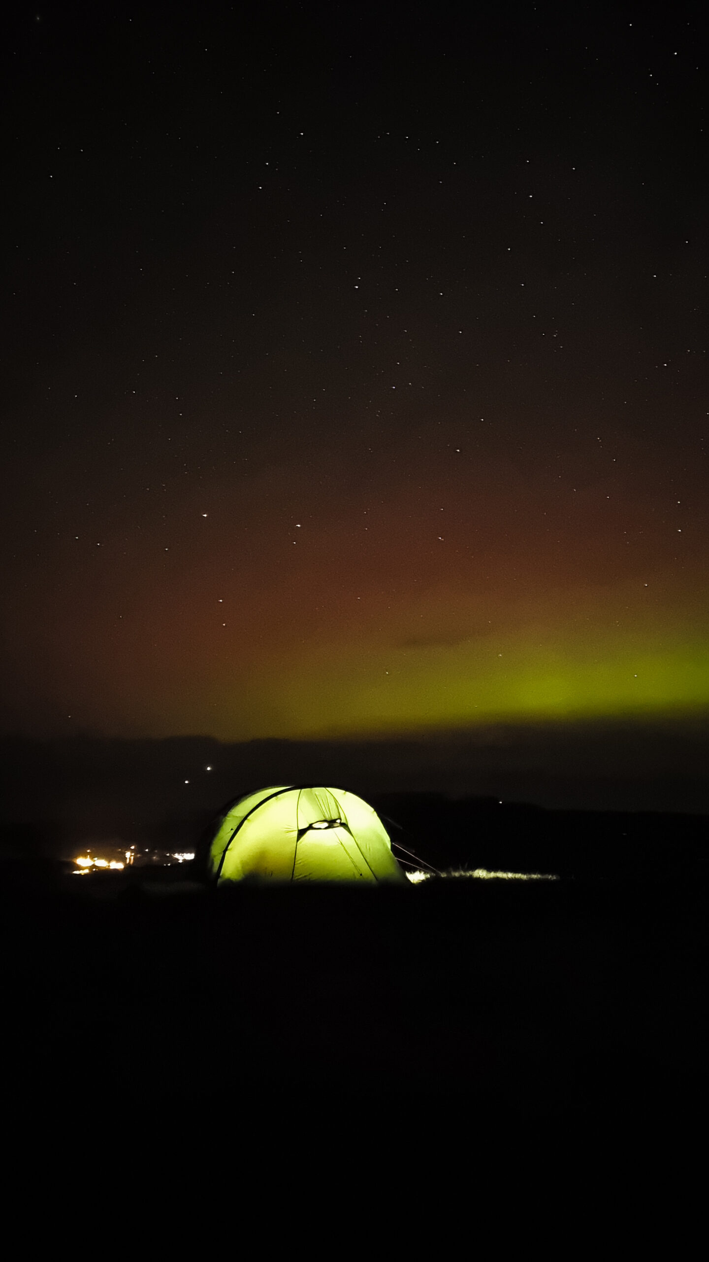 A tent on the summit of Suilven, Scotland with northern lights in the distance