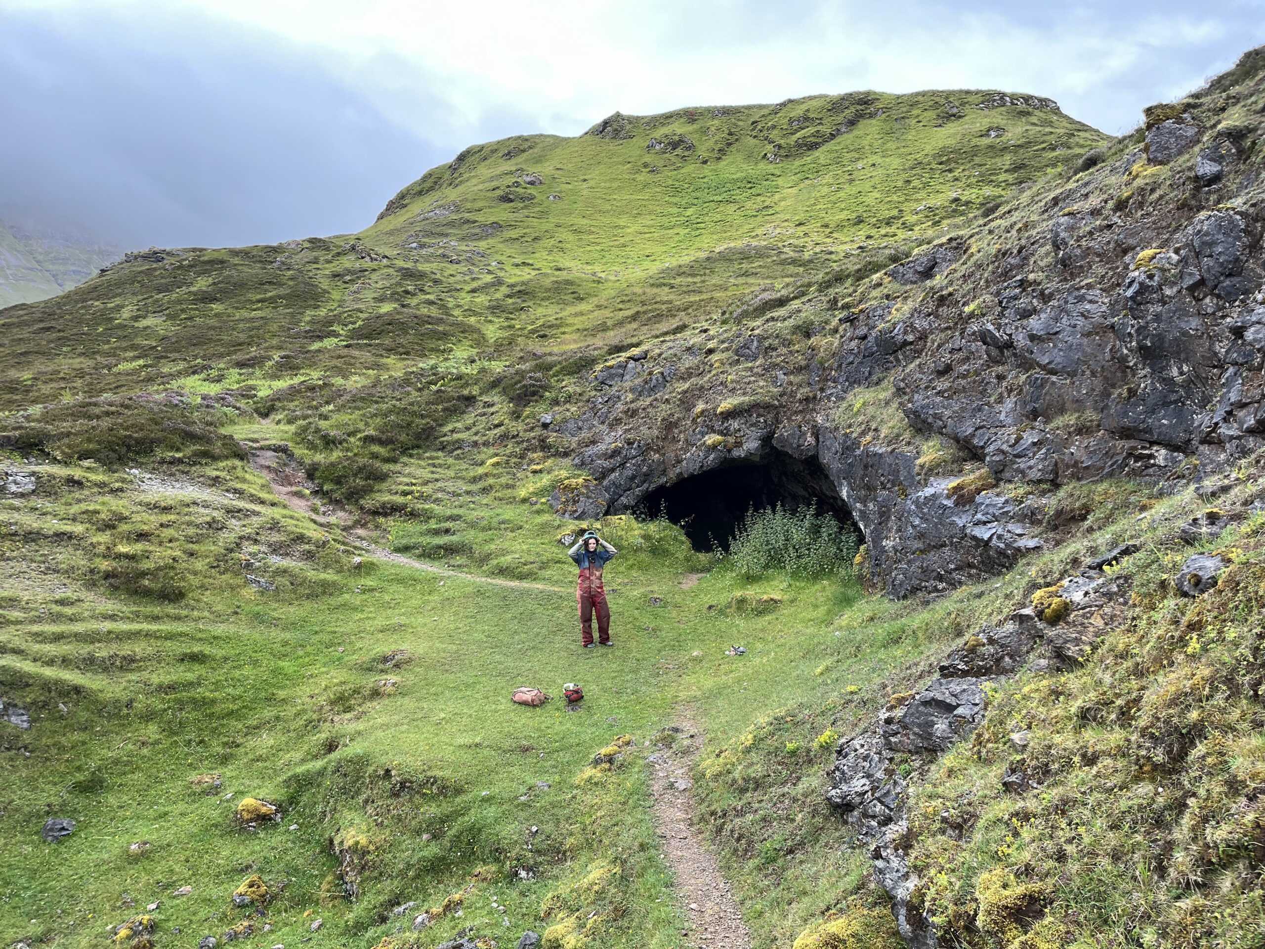 A caver in front of Uamh an Uisge, Cnoc nan Uamh, Scotland