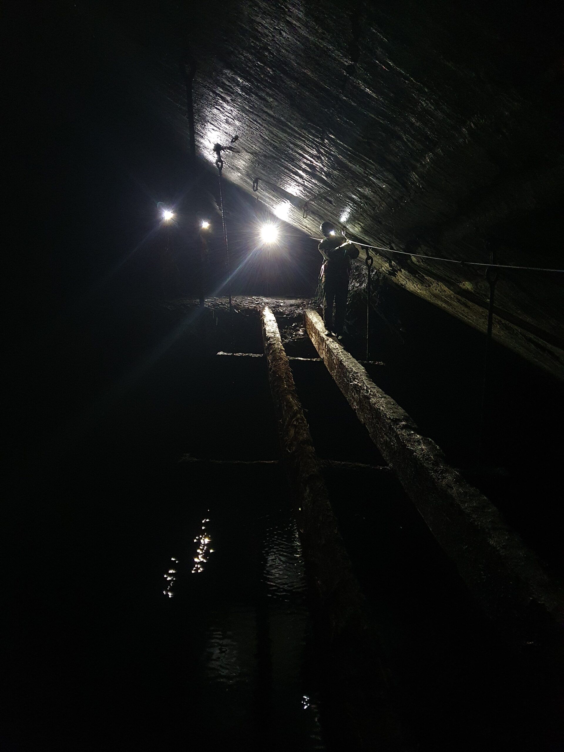 Caver crossing old railway in Croesor-Rhosydd mine, North Wales